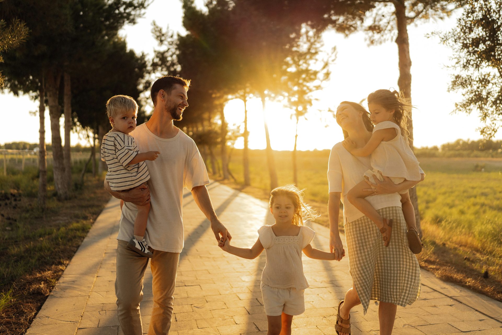 Une famille marche ensemble sur un chemin, au coucher du soleil.